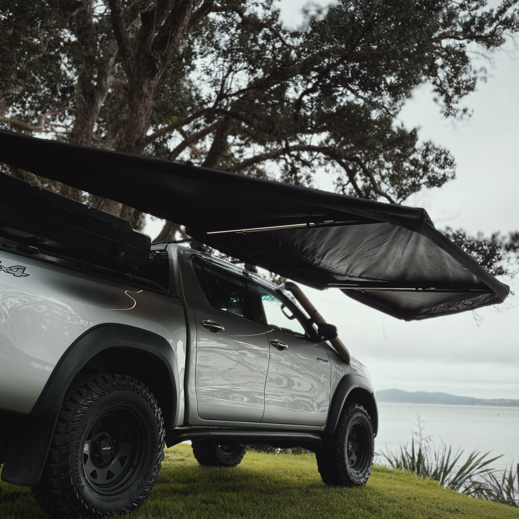 Stoke Mako 180 awning deployed alongside a vehicle for wraparound shade at camp