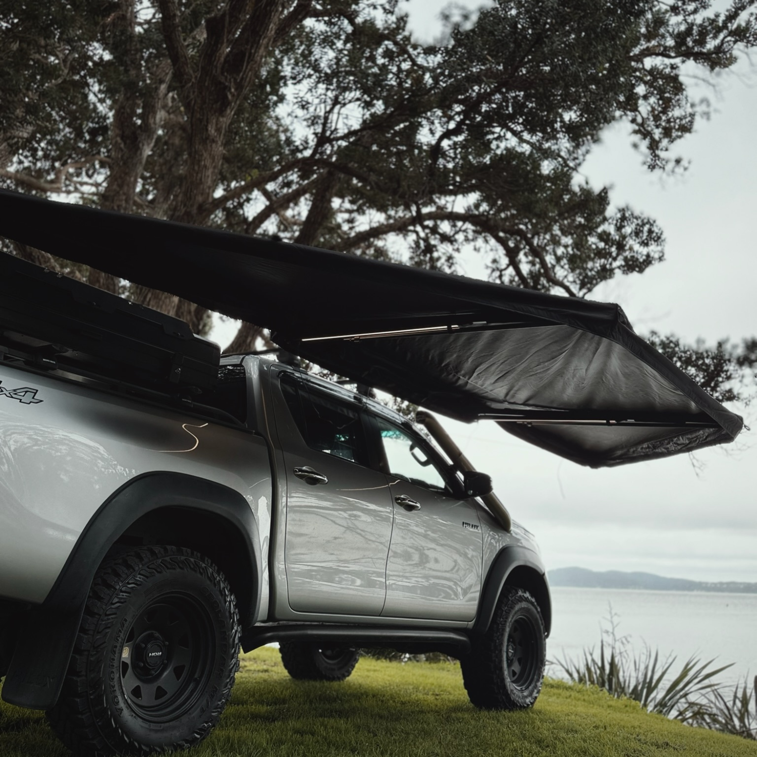 Stoke Mako 180 awning deployed alongside a vehicle for wraparound shade at camp