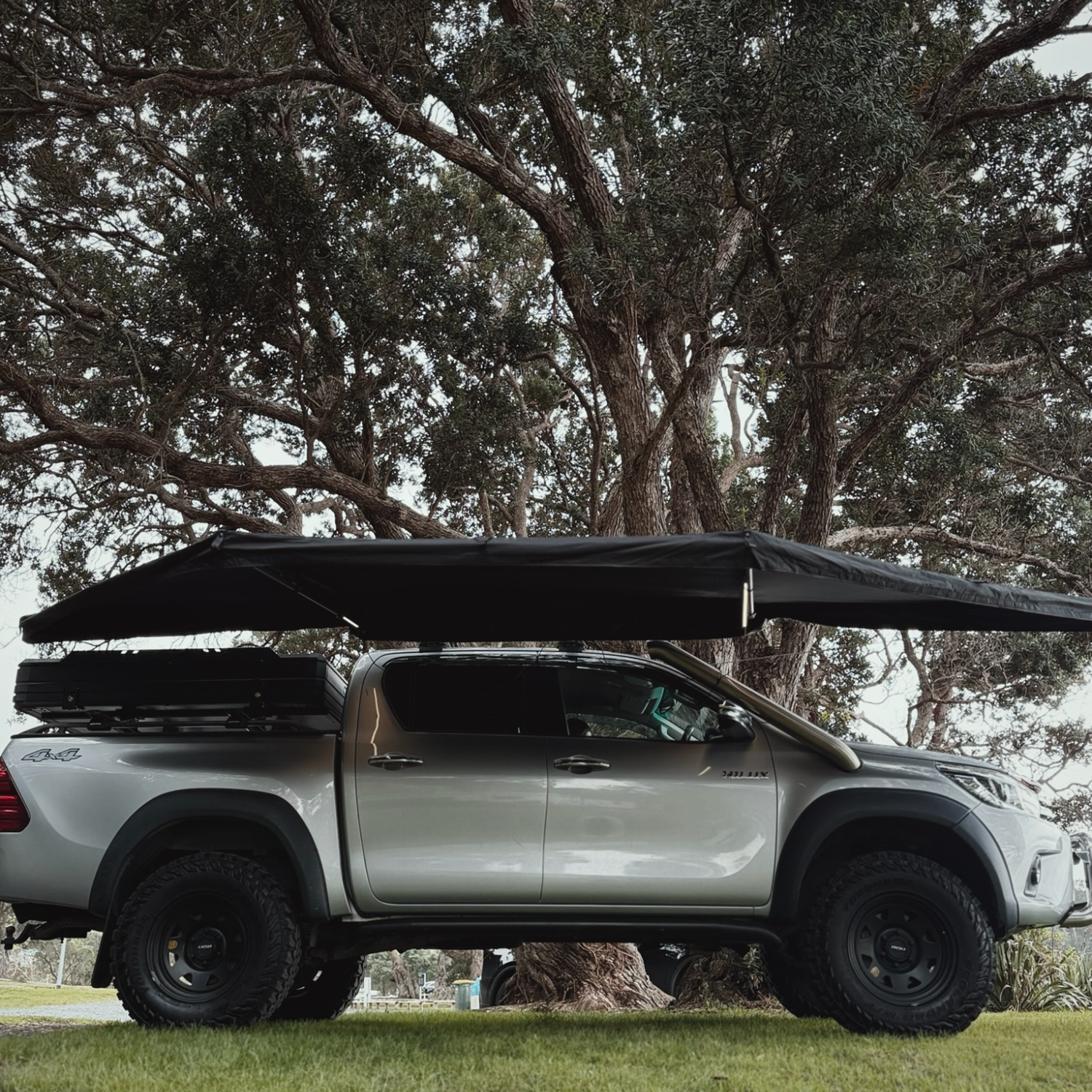 Stoke Mako 180 awning mounted on a 4WD parked on grass, front three-quarter view