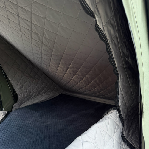 Stoke tent insulation liner lining the interior walls and ceiling at dusk, mattress edge visible