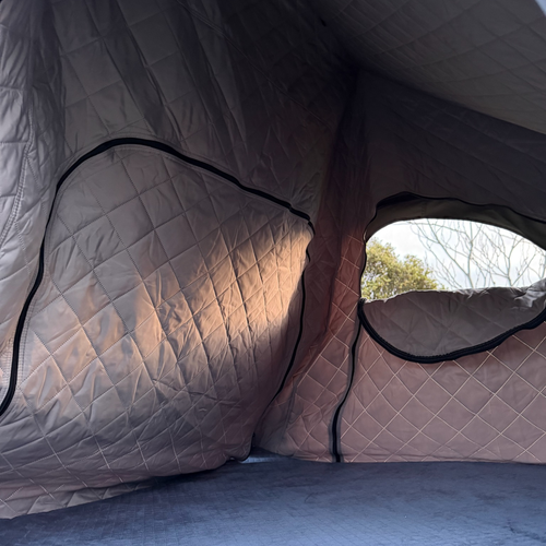 Stoke rooftop tent interior lined with the quilted insulation liner, showing both end windows