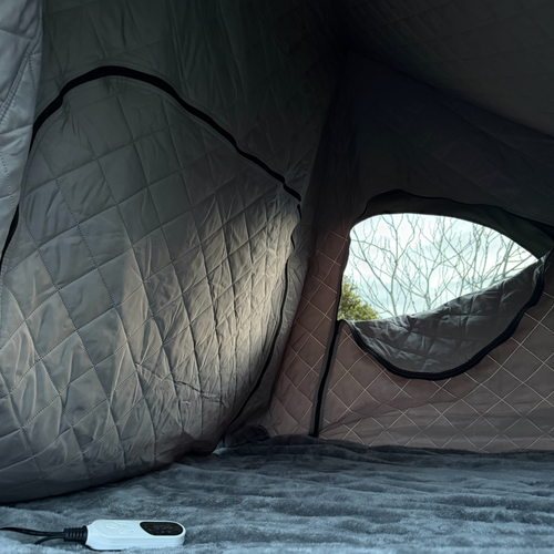 Stoke 12V Electric Blanket XL on a rooftop tent mattress with its corded controller, quilted insulation liner on the walls