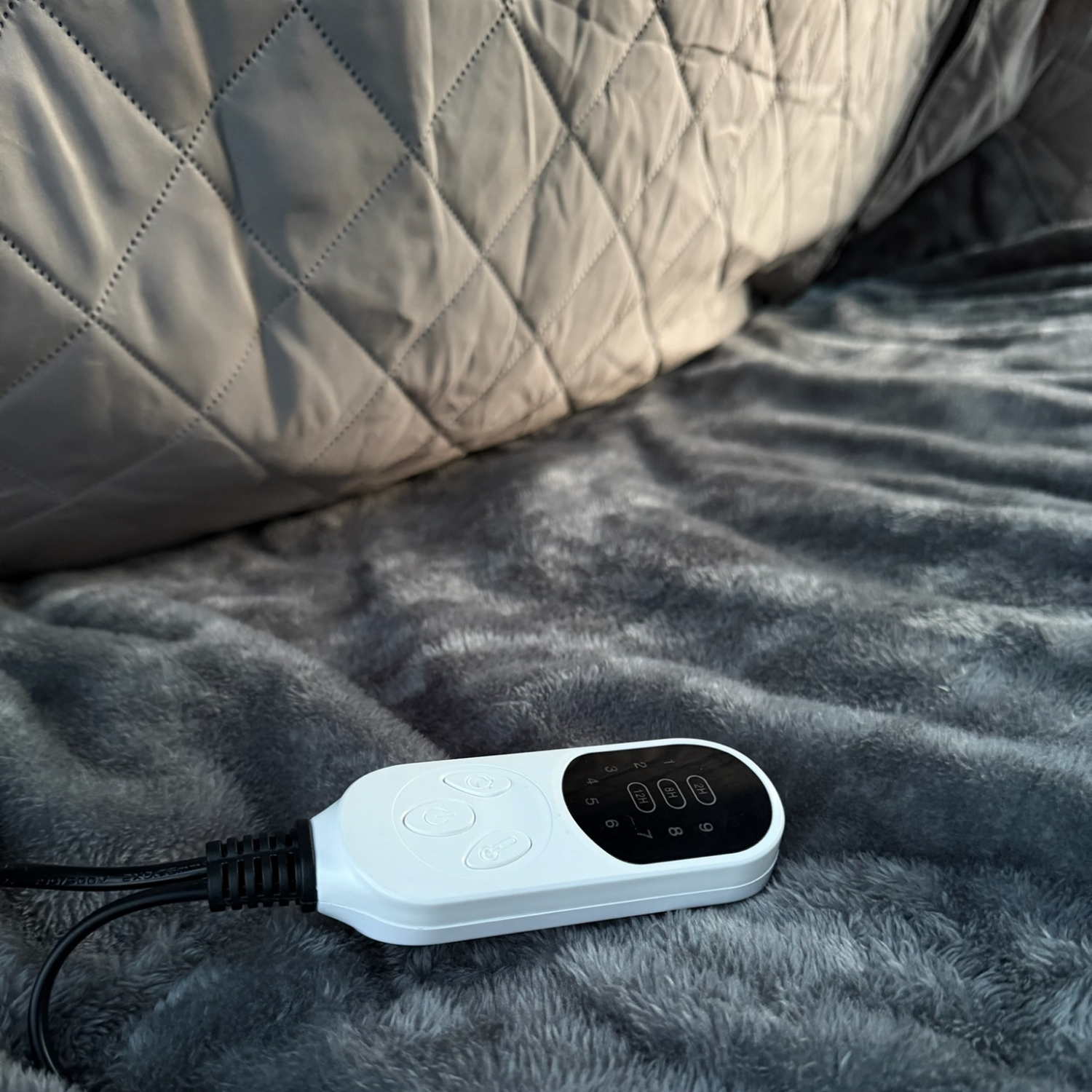 Close-up of the Stoke Electric Blanket XL white controller with digital display and heat settings on the plush blanket