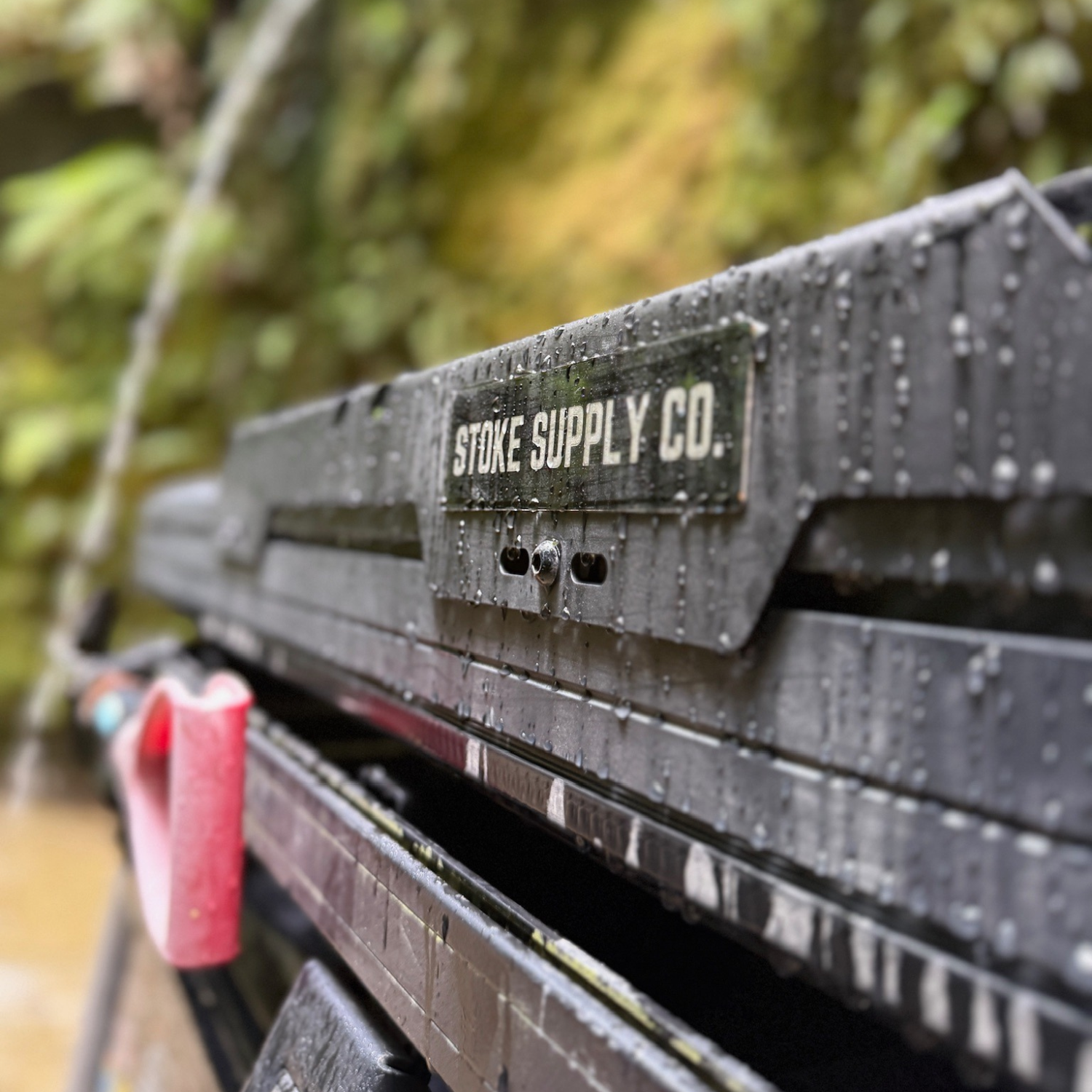 Stoke Supply Co. badge on the slimline crossbar end plate, wet after rain